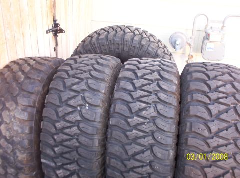 1995 Ford Bronco - Off-road tires are shown leaning against a wall with a gas meter in the background.