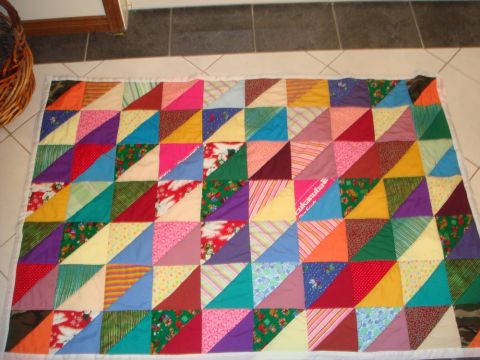 1996 Ford Bronco - A quilt with a patchwork design of colorful triangles is displayed on the floor.