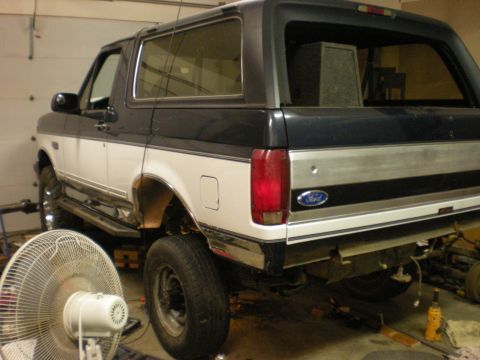 1993 Ford Bronco - The rear of a two-tone Ford Bronco is shown, possibly undergoing repairs or modifications.