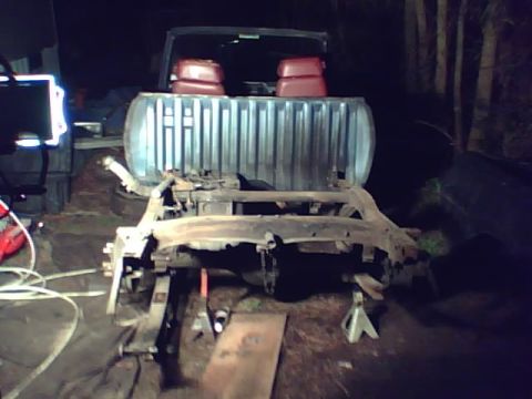 1981 Dodge Power Ram - Disassembled truck chassis resting on jack stands, with the bed and cab visible in the background.