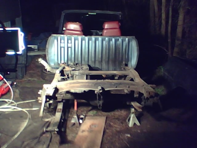 Truck chassis disassembled and supported by jack stands in a workshop