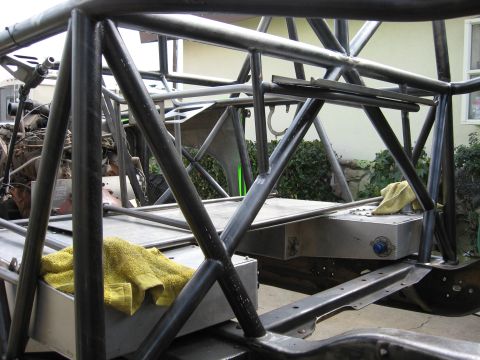1995 Ford Bronco - The custom chassis and roll cage of an off-road vehicle are shown during construction, with a fuel tank and towels in place.