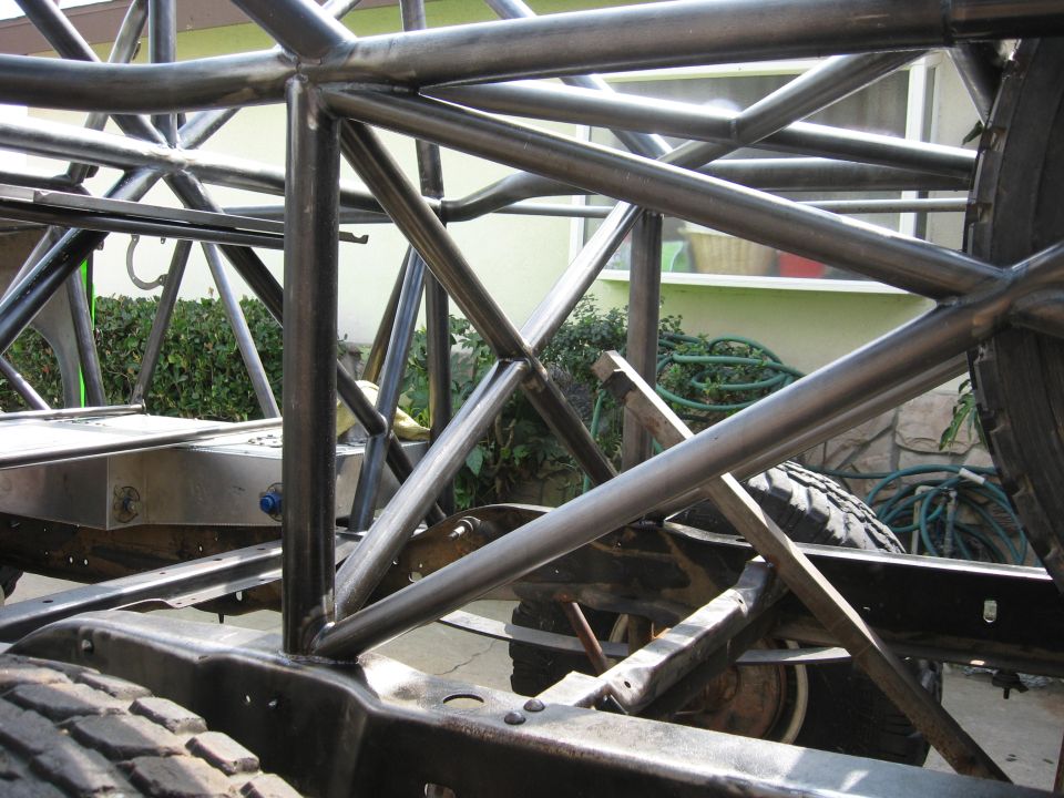 Roll cage and chassis of a vehicle under construction, with visible tires and suspension components