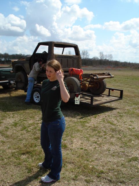 2008 International School Bus - A rusted truck chassis is loaded onto a trailer, with a person attending to it in the background.