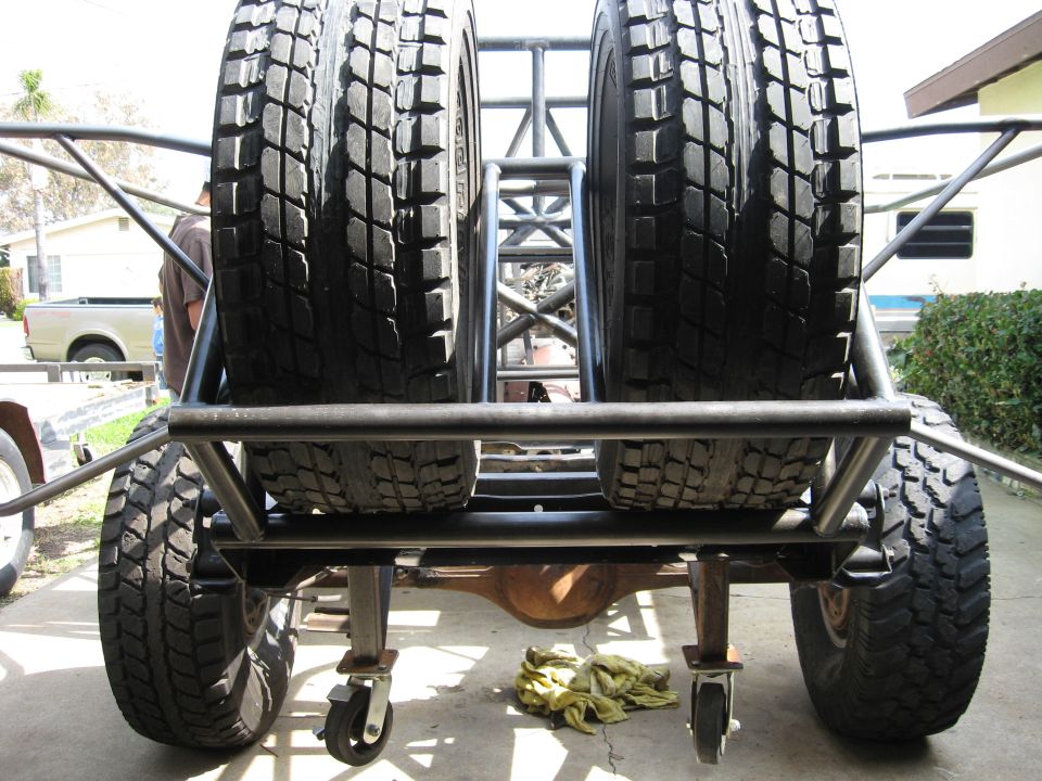 Rear view of a custom off-road vehicle with two spare tires mounted vertically on a metal rack