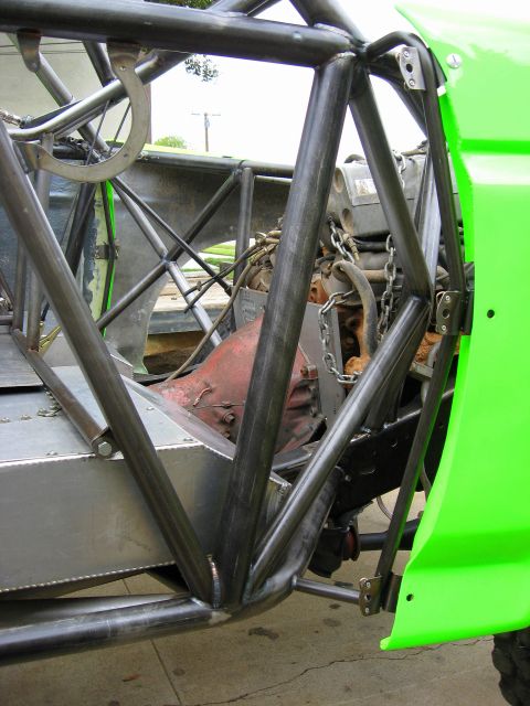 1995 Ford Bronco - The intricate metal framework of a custom-built off-road vehicle is visible, surrounding the engine and transmission.