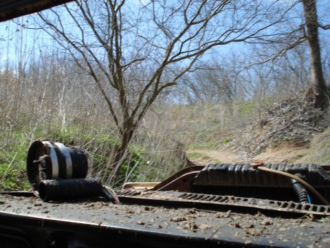 2008 International School Bus - A close-up view of a truck's radiator and a tire, set against a backdrop of trees and a dirt path.