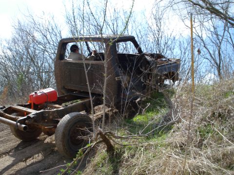 2008 International School Bus - A heavily weathered truck chassis, missing its body, navigates a dirt path.