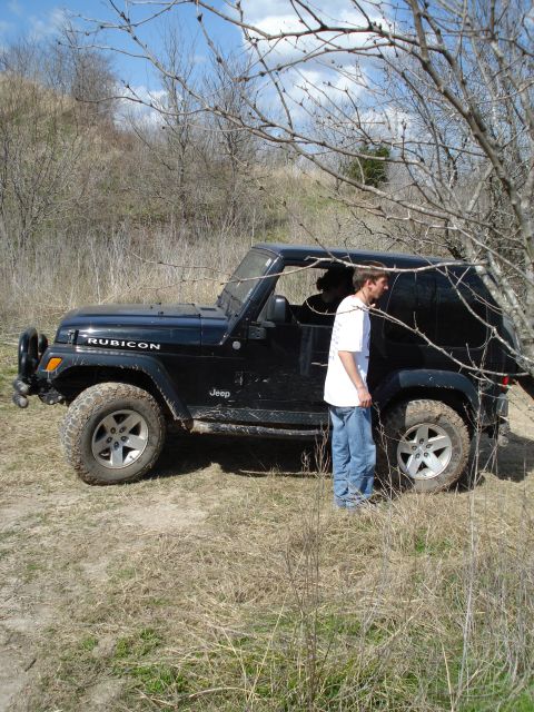 2008 International School Bus - A black Jeep Wrangler Rubicon is parked off-road with a person standing by the driver's side door.
