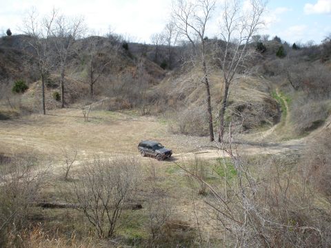 2008 International School Bus - A dark SUV navigates a dirt road through a barren, hilly terrain under a bright sky.