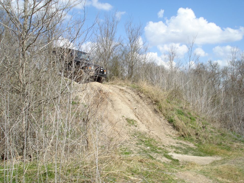 Dark SUV climbing a dirt hill through dry brush