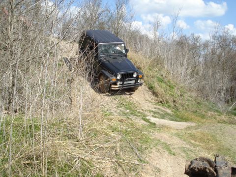 2008 International School Bus - Jeep Wrangler navigating a steep, dry dirt trail with sparse vegetation.