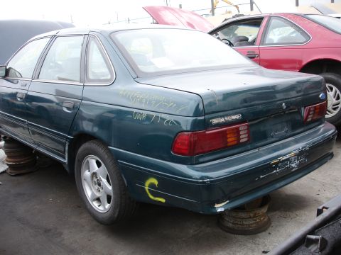 1993 Ford Taurus - Rear view of a green 1993 Ford Taurus sedan in a junkyard.