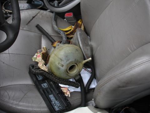 1993 Ford Taurus - The interior of a vehicle is filled with various car parts, including a coolant reservoir and fuse box, alongside a ripe banana.