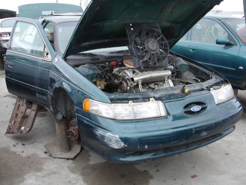 1993 Ford Taurus - The engine bay of a 1993 Ford Taurus is visible with the hood open, showing the engine and cooling fan.
