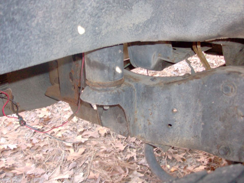 Vehicle frame with air suspension bag and rusty metal components visible