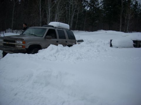 2000 Chevrolet Tahoe - This SUV is buried in a large snowdrift, indicating difficult winter driving conditions.