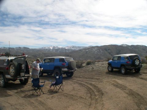 2007 Toyota FJ Cruiser - Three 2007 Toyota FJ Cruisers are parked off-road with a mountain range visible in the background.