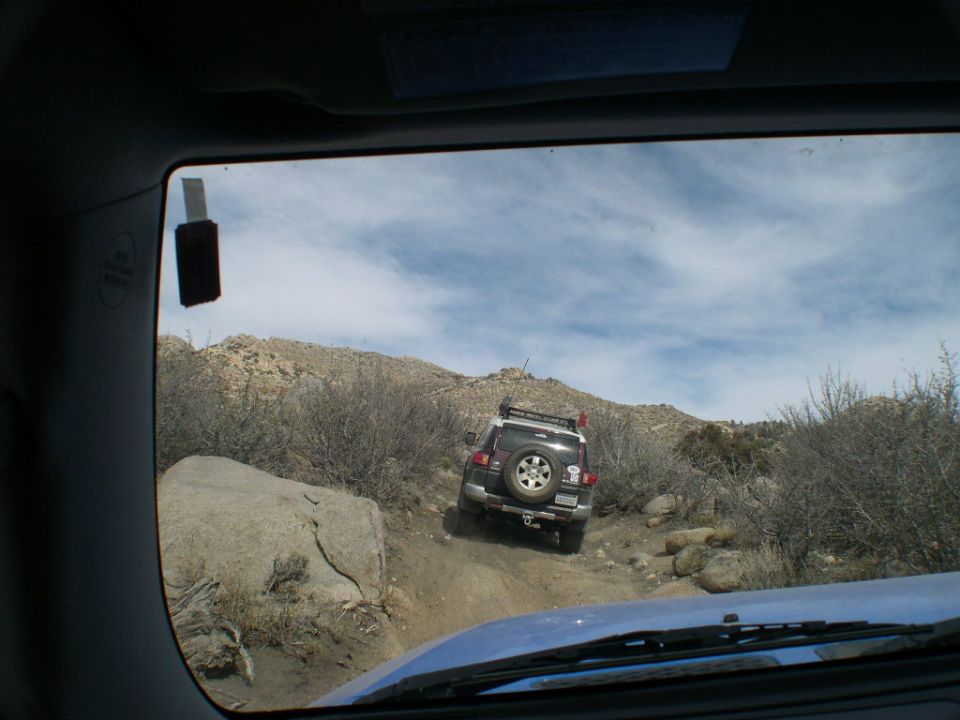 View through rear window of an SUV crawling over rocks on a trail