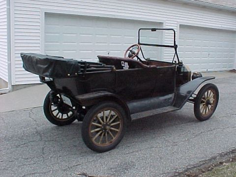 1913 Ford Model T - This 1913 Ford Model T touring car features a dark body, wooden spoke wheels, and a convertible top folded down at the rear.
