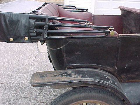 1913 Ford Model T - The rear passenger side of a 1913 Ford Model T touring car, its burgundy interior and black canvas top, is visible.