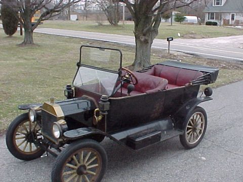 1913 Ford Model T - A 1913 Ford Model T touring car with its top up sits parked on a paved surface.