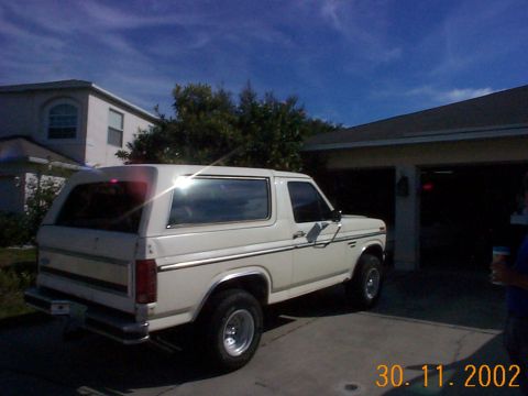 1985 Ford Bronco - White SUV parked in a driveway with a garage in the background.