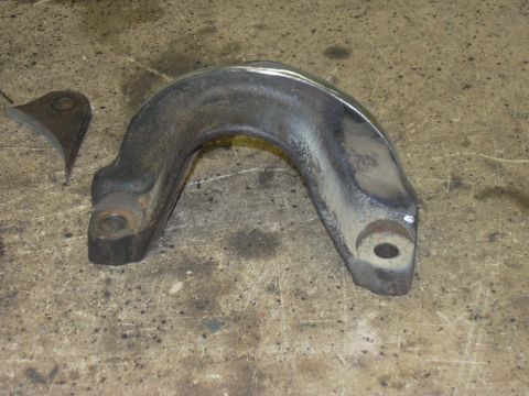 1991 Ford Bronco - A cast iron radius arm bracket sits on a concrete surface next to a smaller metal piece.