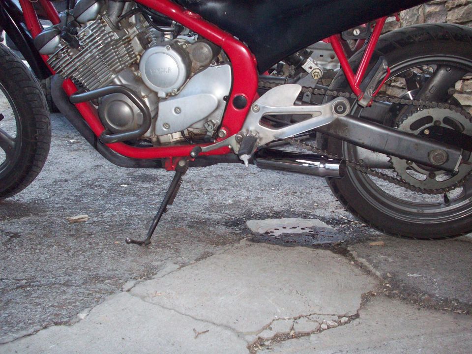 Motorcycle engine and rear wheel with red frame and chrome exhaust