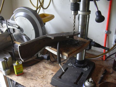 1991 Ford Bronco - A metal part is being drilled on a drill press, with a miter saw visible in the background.