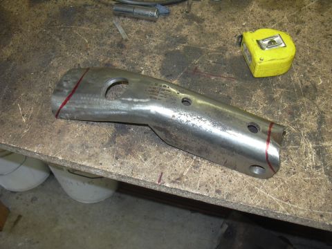 1991 Ford Bronco - A metal component with drilled holes and marked cut lines rests on a cluttered workbench.