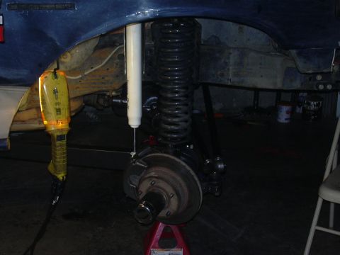 1991 Ford Bronco - Close-up of a vehicle's front suspension system, showing the shock absorber, coil spring, and brake components.