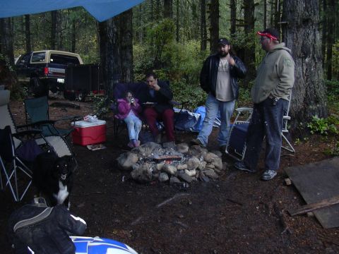 1991 Ford Bronco - A 1991 Ford Bronco with a camper shell is parked at a campsite where people are gathered around a fire.