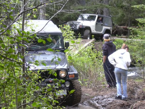 1991 Ford Bronco - Off-roading adventure with two Jeeps navigating a wooded trail and crossing a bridge.
