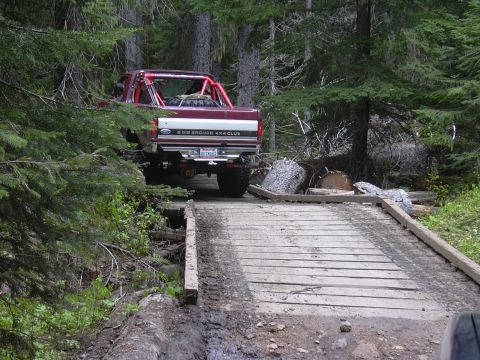 1991 Ford Bronco - A red 1991 Ford Bronco 4x4 Club cab navigates a wooden bridge in a wooded area.