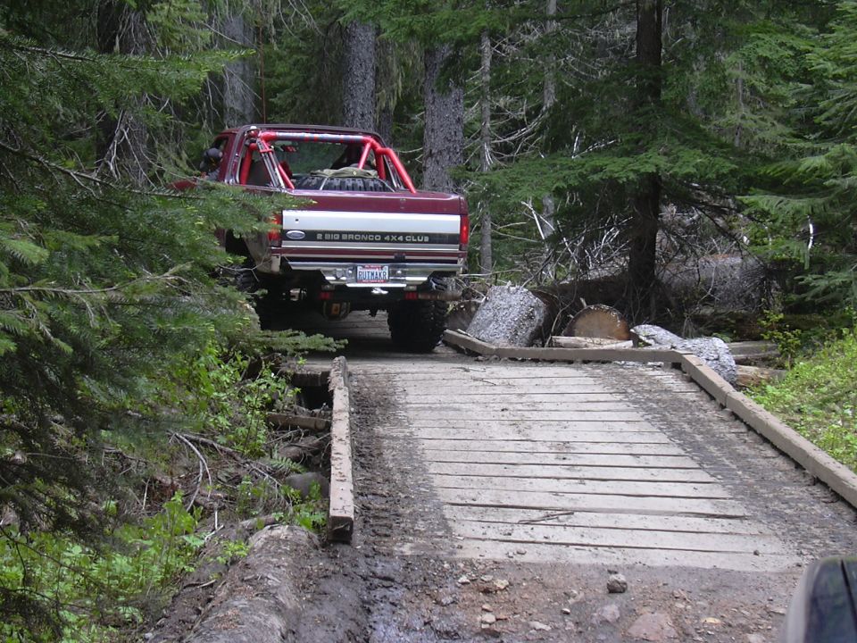 Red 1991 Ford Bronco 4x4 Club cab on a wooden bridge in a forest