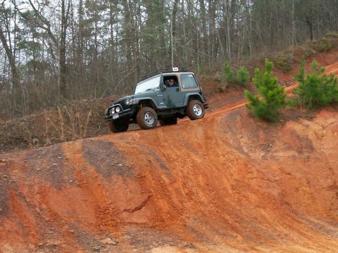 1993 Ford Bronco - A Jeep Wrangler TJ navigates a challenging off-road trail with steep inclines and loose dirt.