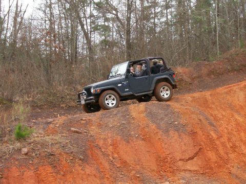 1993 Ford Bronco - A Jeep Wrangler navigates an off-road trail on a dirt incline.