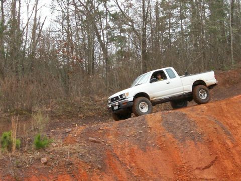 1993 Ford Bronco - This Toyota Tacoma is navigating a steep, muddy incline on a wooded trail.