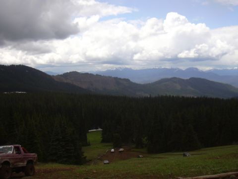 1991 Ford Bronco - Off-road vehicles gathered in a scenic mountain landscape with a forest and distant peaks.