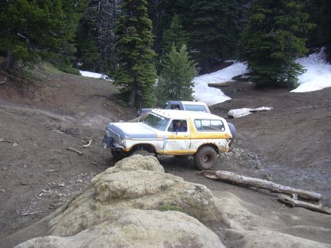 1991 Ford Bronco - A vintage Ford Bronco navigates a challenging off-road course with snow patches visible on the surrounding hills.