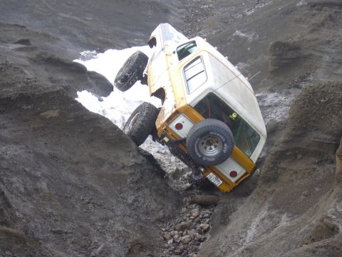 1991 Ford Bronco - This off-road vehicle is stuck in a steep ravine, its tires struggling for traction on the rocky terrain.