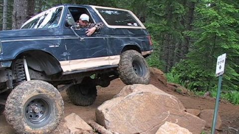 1991 Ford Bronco - A modified Ford Bronco navigates a challenging rocky terrain on an off-road trail.