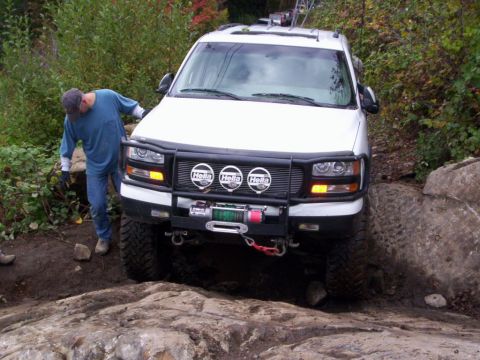 1991 Ford Bronco - A white SUV with off-road modifications navigates a rocky trail.