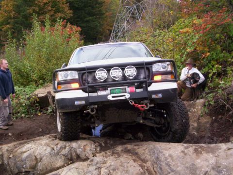 1991 Ford Bronco - This modified truck navigates a challenging rocky trail with assistance from onlookers.