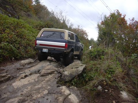 1991 Ford Bronco - Ford Bronco tackling a challenging off-road course on a cloudy day.