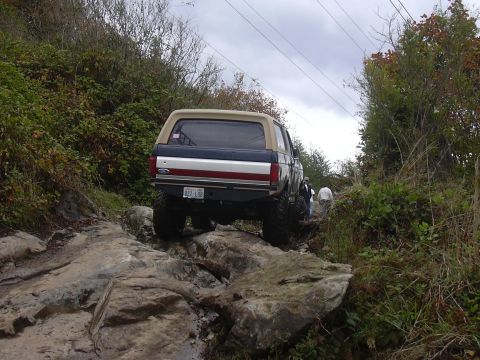 1991 Ford Bronco - A lifted Ford Bronco tackles a challenging rocky terrain on an overcast day.