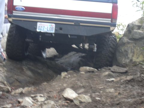 1991 Ford Bronco - This Ford Bronco is navigating a rocky trail, showing its rear bumper and tires.