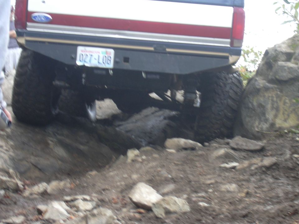 Rear view of a 1991 Ford Bronco driving over rocks