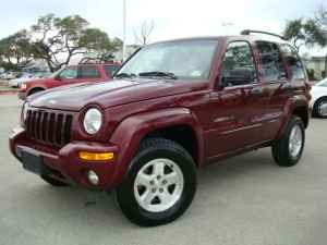 1989 Ford Bronco - A maroon Jeep Liberty is parked in a lot with other vehicles visible in the background.